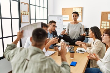 Wall Mural - Businesswoman enjoys meditating during meeting. Sitting on desk near arguing partners at the office.