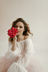 Wall Mural - Charming pretty lady with blond hair in modern light fluffy dress looking into camera with bright flowers on isolated background..