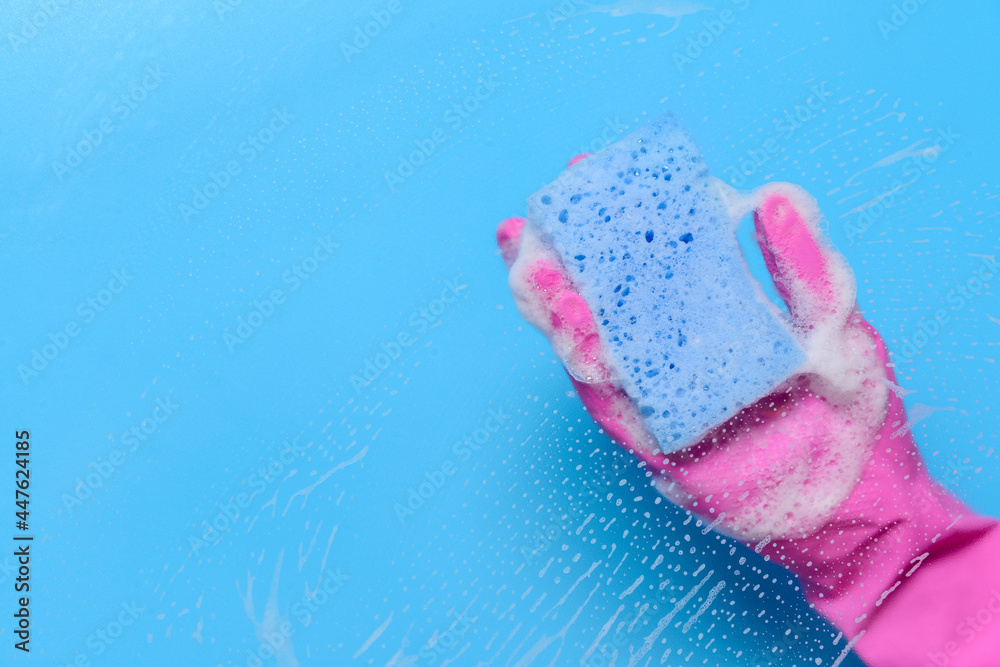 Woman with sponge cleaning color surface