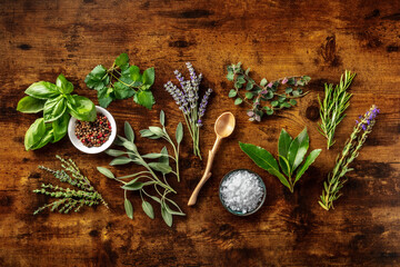 Wall Mural - Fresh aromatic herbs, overhead flat lay shot on a rustic wooden background with spices. Bunches of rosemary, basil, thyme, lavender, and various other culinary plants