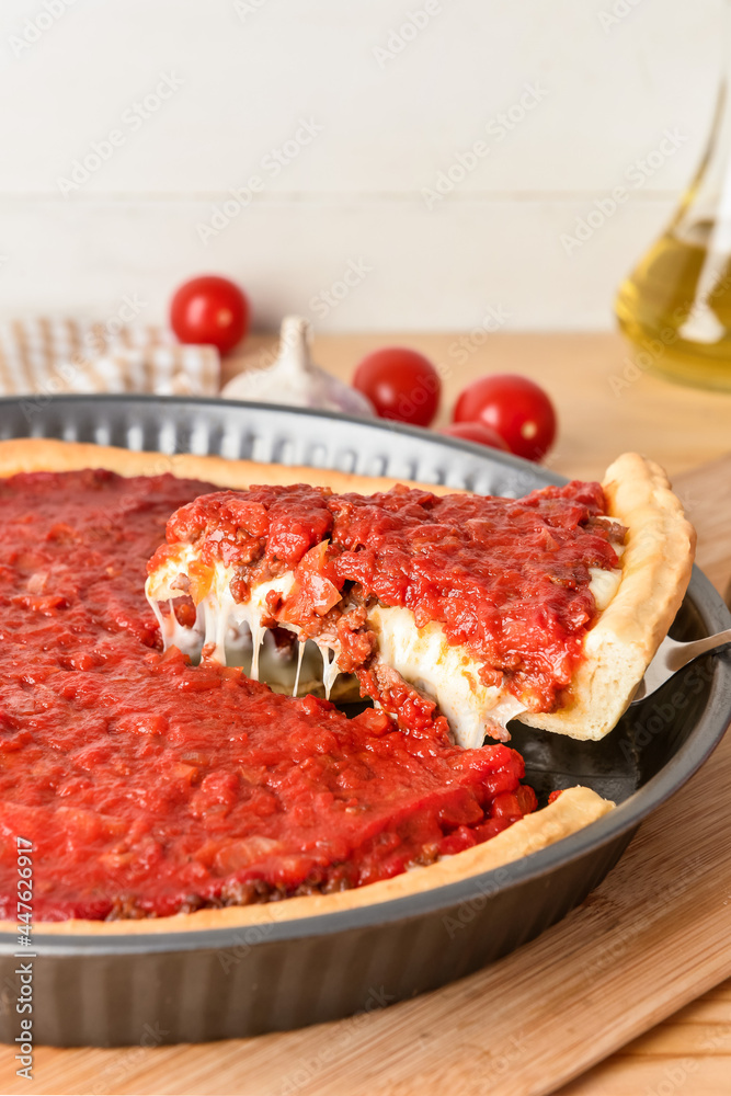 Baking dish with tasty Chicago-style pizza on light background