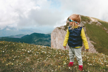 Traveler child girl hiking in mountains family vacations healthy lifestyle hobby 2 years old toddler walking outdoor wearing sunglasses