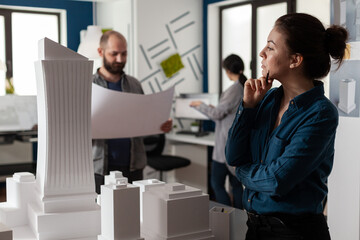 Poster - Professional architects working on blueprints plan to design building model maquette construction layout. Team of caucasian workers discussing industry project for engineering