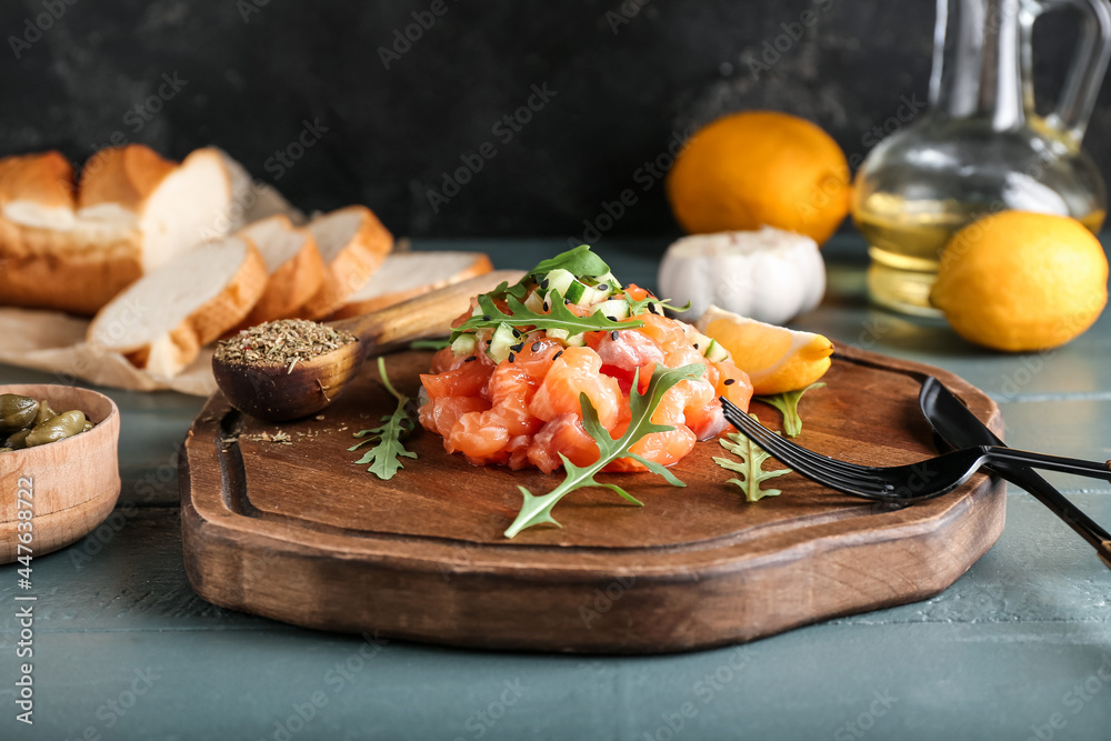Delicious salmon tartar on color wooden background