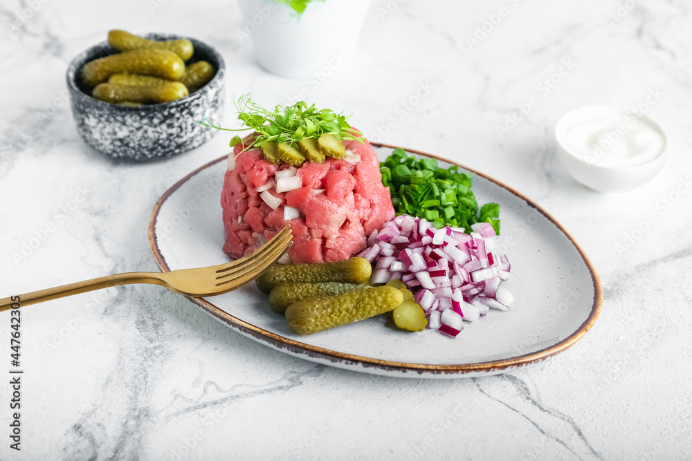 Plate with tasty beef tartare on light background