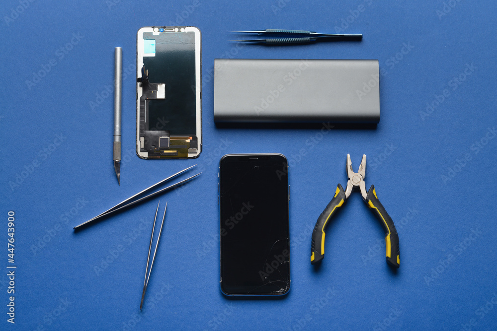 Disassembled mobile phone with technician tools on color background