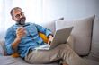 © Dragana Gordic - Attractive bearded hipster mature man using Laptop and credit card payment shopping online with customer network connection via omni channel system. Older man with technology.