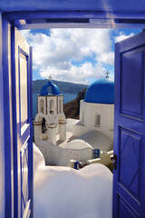 Wall Mural - Santorini view with churches against old open blue door in Oia village, Greece