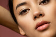 Cropped close-up image of beautiful female face isolated on brown studio background.