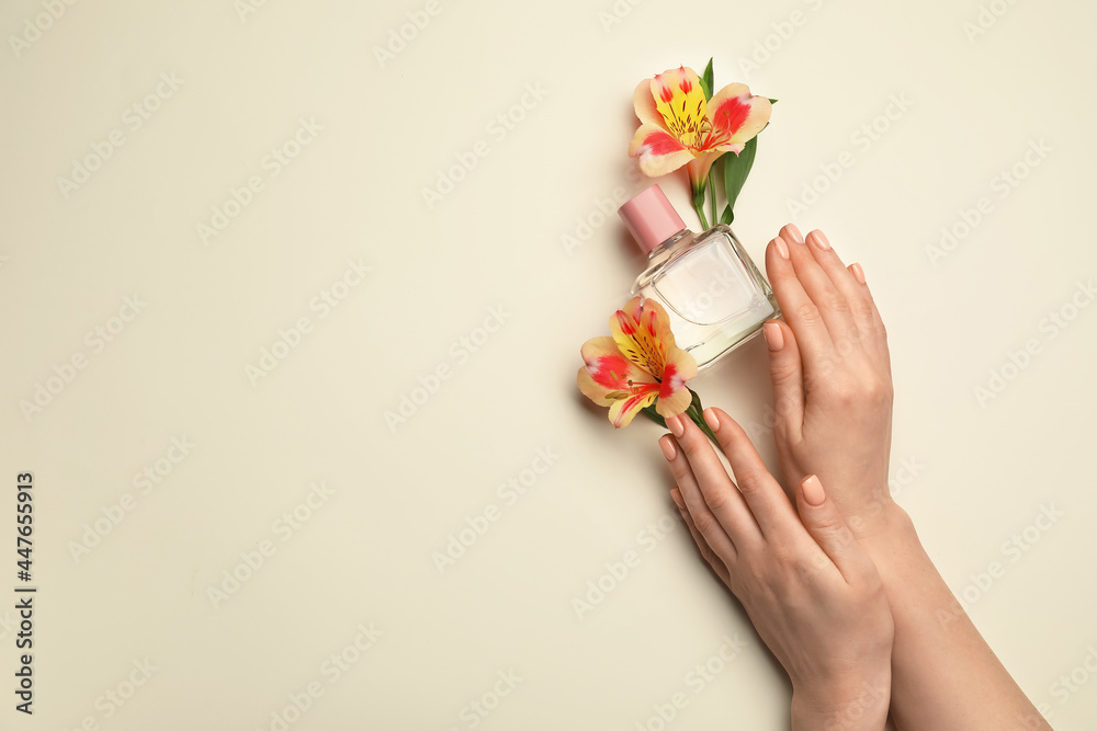 Hands with beautiful manicure, flowers and perfume on light background