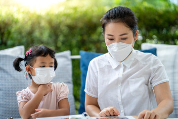 Wall Mural - Young mother and little girl wearing protective face mask  sitting at restaurant.