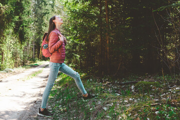 Pretty teen young tourist girl relaxing on forests road.Teenage with backpack on green forest summer or spring.