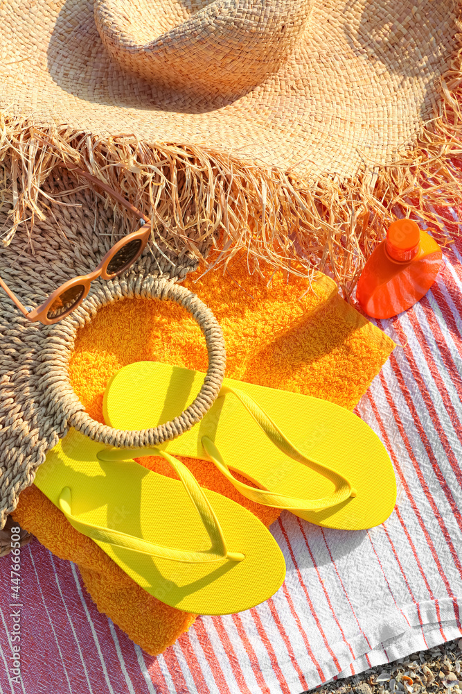 Bag with flip-flops and beach accessories on sand, closeup