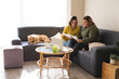 © Wavebreak Media - Lesbian couple using laptop and sitting on couch with dog