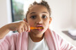 © Wavebreak Media - Portrait of mixed race girl brushing teeth in bathroom