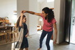 © Wavebreak Media - Happy mixed race mother and daughter dancing in living room