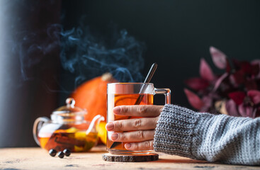 A woman in a sweater holds a mug of hot tea with lemon. Autumn time. 