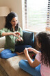 © Wavebreak Media - Mixed race mother and daughter sitting on sofa, gesturing and playing together