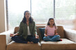 © Wavebreak Media - Mixed race mother and daughter sitting on sofa and meditating