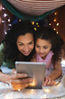 © Wavebreak Media - Portrait of happy mixed race mother and daughter using laptop in makeshift tent