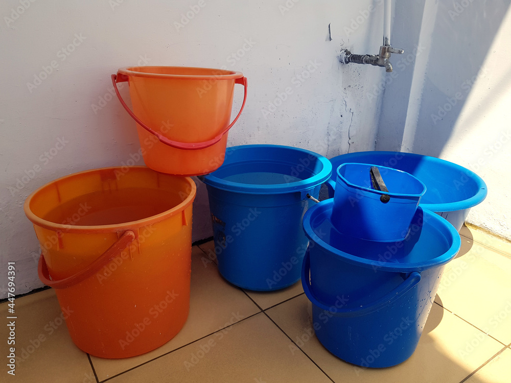 The blue and orange plastic bucket which filled with water near the ...