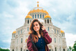 Young beautiful woman walks on the square with the Sea Cathedral in Kronstadt, Russia