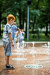 Young boy in the summer fountain in the park. Summer vacation time.