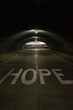 © RooM The Agency - Word hope written on a road with light at the end of a tunnel, USA