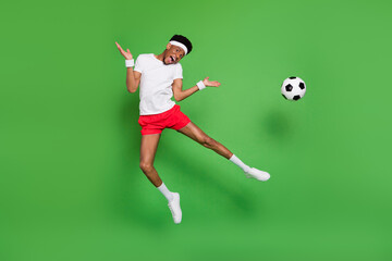 Wall Mural - Photo of funky active guy jump kick ball wear headband white t-shirt shorts footwear isolated green color background