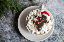 Christmas Gingerbread Man In A Santa Hat Cookie Next To A Cup Of Mini Marshmallows