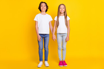 Canvas Print - Full length body size view of two attractive cheerful kids holding hands spending time isolated over bright yellow color background