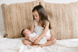 © ADDICTIVE STOCK - Smiling girl sitting with newborn on bed
