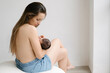 © ADDICTIVE STOCK - Mother breastfeeding baby in room at home