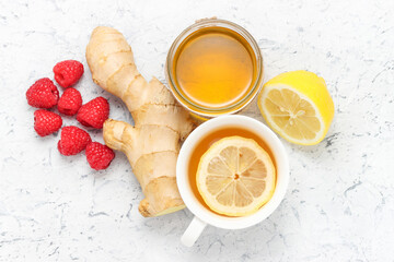 cup of tea with lemon, jar of honey, ginger root with raspberries, healthy ingredients to cure flu and cough at home