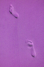 Surreal Pop Art Purple Colored Footprints On The Wet Sandy Beach