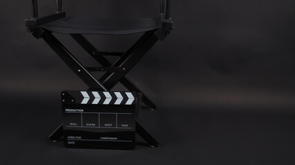 Director chair and black clapper board or movie slate use in video production, movie, film, cinema industry on black background.