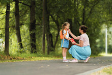 Caring Mother Accompanies Child To School. Parent Encourages Student To Accompany Him To School. Woman Looks Tenderly At Her Daughter Going To School. Little Girl Goes To Primary School With Pleasure