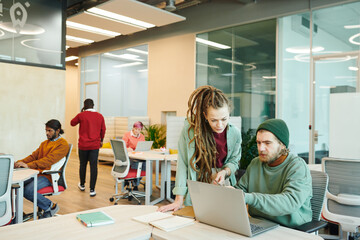 Wall Mural - Two young contemporary office managers in casualwear looking at laptop display