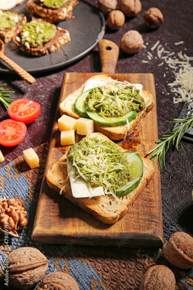 Tasty toasts with pesto sauce on dark background