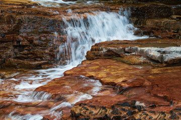 Wall Mural - Water flowing over brown rocks