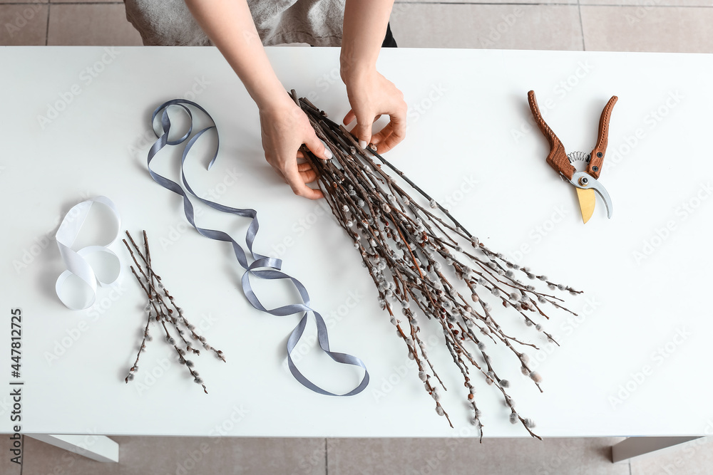 Woman making bouquet of willow branches on table