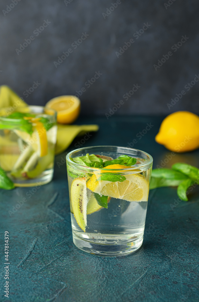 Glass of tasty lemonade with basil on dark background