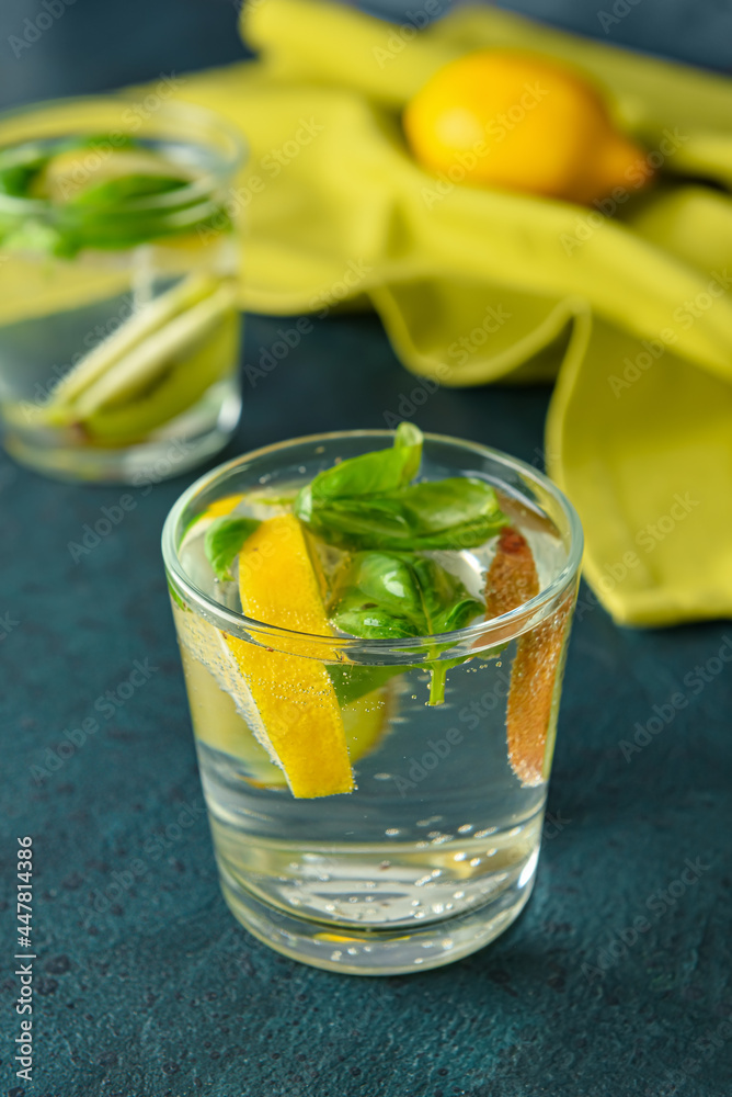 Glass of tasty lemonade with basil on dark background