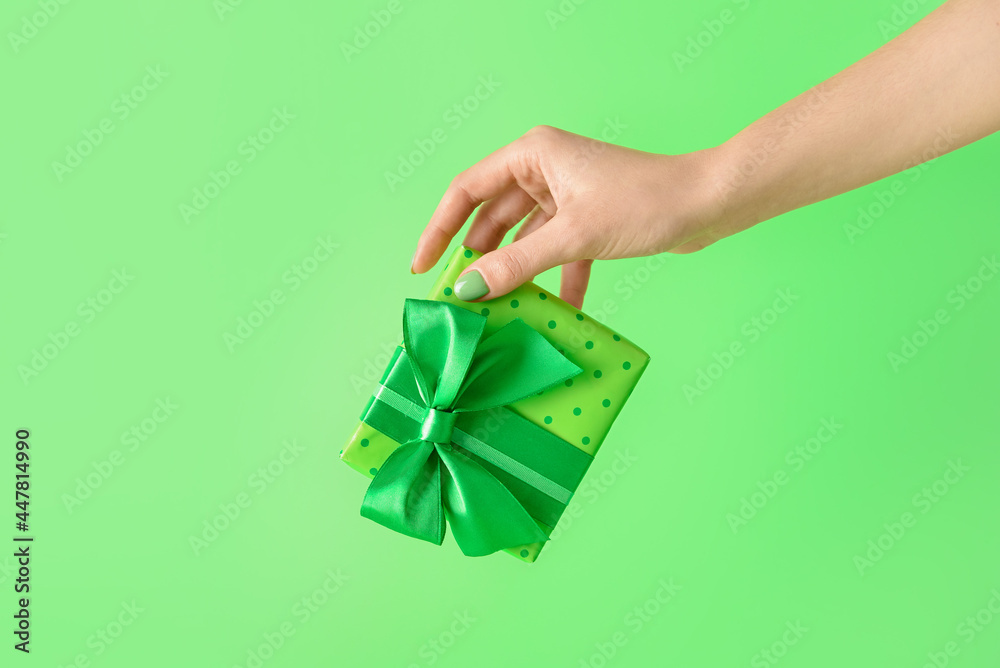 Female hand with gift box on color background - obrazy, fototapety, plakaty 