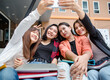 © Bangkok Click Studio - Group of four young attractive asian girls college students use mobile phone taking selfie photo smiling in university campus outdoor. Concept for education, friendship and college students life