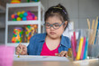© Bangkok Click Studio - Young Asian down syndrome little girl sitting at desk with colors and painting with concentrated and calm. painting. Concept for education for disabled kid