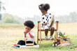 Two African American little boy and girl playing toy together in the park. Children with curly hair having fun together outdoor. Black kid people enjoying outside