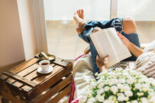 Young Woman Is Relaxing At Home, Drinking Tea, Reading Book