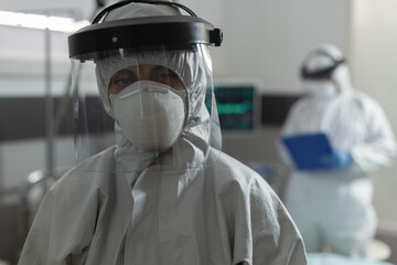 Wall Mural - Medical specialist with face mask dressed in coverall, during coronavirus pandemic outbreak , to prevent infection with covid-19. Doctor taking notes on clipboard talking with patient.