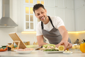 Poster - Man making dinner while watching online cooking course via tablet kitchen